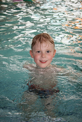 Junge schwimmt im Hallenbad
