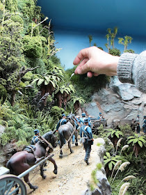 Man straightening a piece of miniature toetoe grass in a diorama bush scene.