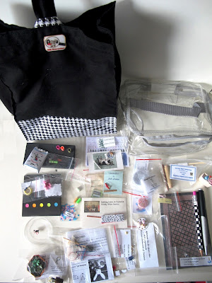 Black and white goodie bag, with its miniature-related contents arranged around it.
