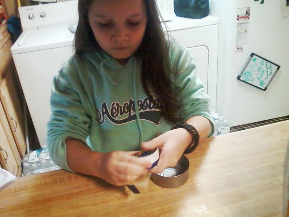 After cutting a 1 in strip off of a pepsi can she rolled it into coil.