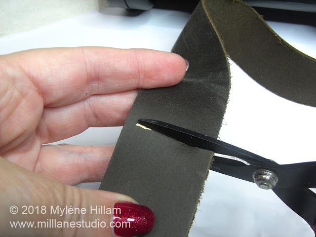 Using scissors to cut the leather belt to size