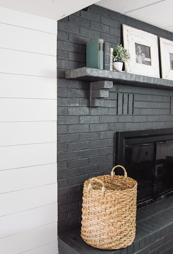 A gorgeous dark gray painted fireplace looks stunning paired with a bright white plank wall! - www.littlehouseoffour.com