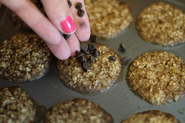 Mini chocolate chips being added to the top of the morning oatmeal muffin bites. 