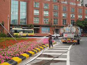 man watering flowers with hose connected to a water truck