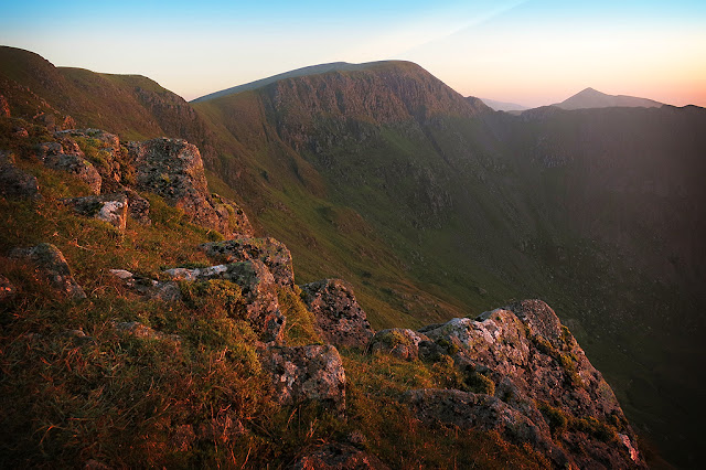 A warm glow lighting up striding edge and the Helvellyn range, sunrise, wild camp
