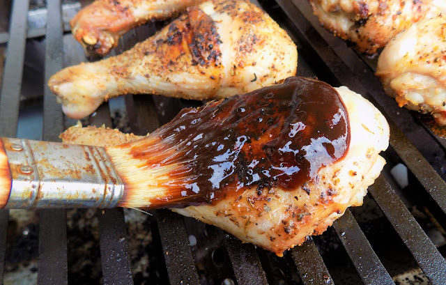 This is a picture of freshly grilled chicken legs being basted with barbecue sauce