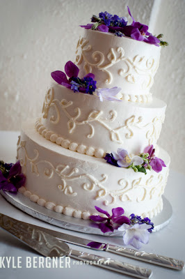 White wedding cake with purple flowers and swirls