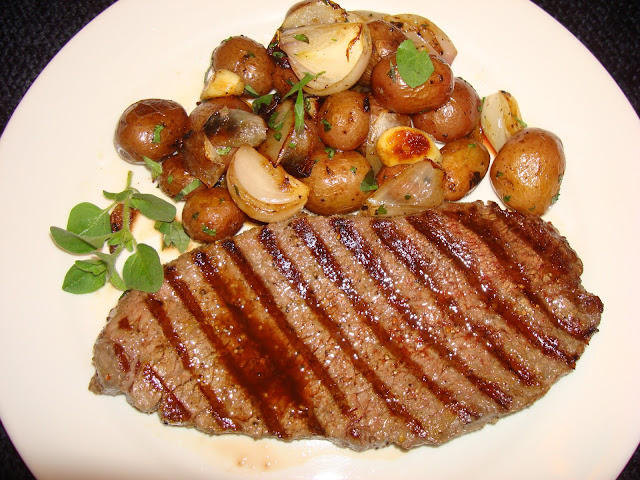 GRILLED BEEF SHOULDER STEAK AND PAN ROASTED KLONDIKE  PETITE POTATOES WITH GARLIC AND SHALLOTS PORTIONS: 2 INGREDIENTS TO SEASON THE STEAK 2 – 8 oz. shoulder steaks 2 tsp. olive oil 2 minced garlic cloves ¾ tsp. coarse sea salt or to taste ¼ tsp. ground pepper Combine oil with garlic and pepper and brush the steaks. Add salt at the time you are cooking the steak. Heat up well a top stove griddle. Mark and cook the steak lightly charred or at your taste. INGREDIENTS FOR THE ROASTED POTATOES 2 cups Klondike petite potatoes, washed. (12 oz.) 1 cup water 2 tbsp. olive oil ½ cup peeled shallot 8 garlic cloves Salt and pepper to taste 2 tbsp. chopped fresh oregano. In a frying pan boil the water, add the potatoes and cover. Cook the potatoes until just done. Let the water to evaporate.  Add the oil, shallot, garlic and cook until they are lightly brown. Sprinkle with fresh oregano and serve.