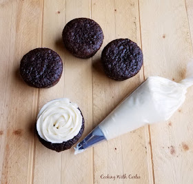 Adding a little "liquid gold" sweetened condensed milk to buttercream makes it feel extra special. It add that little bit of rich depth of flavor you can't get anywhere else! chocolate banana cupcakes with a piping bag full of sweetened condensed milk frosting
