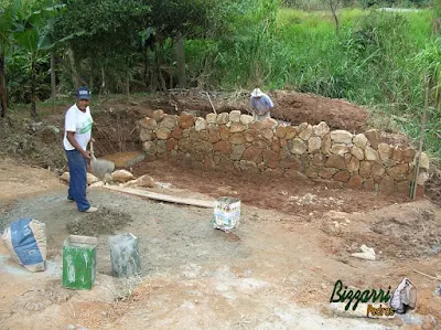 Construção do muro de pedra com pedra bruta para a base da construção da ponte de concreto na entrada da empresa em Atibaia-SP.