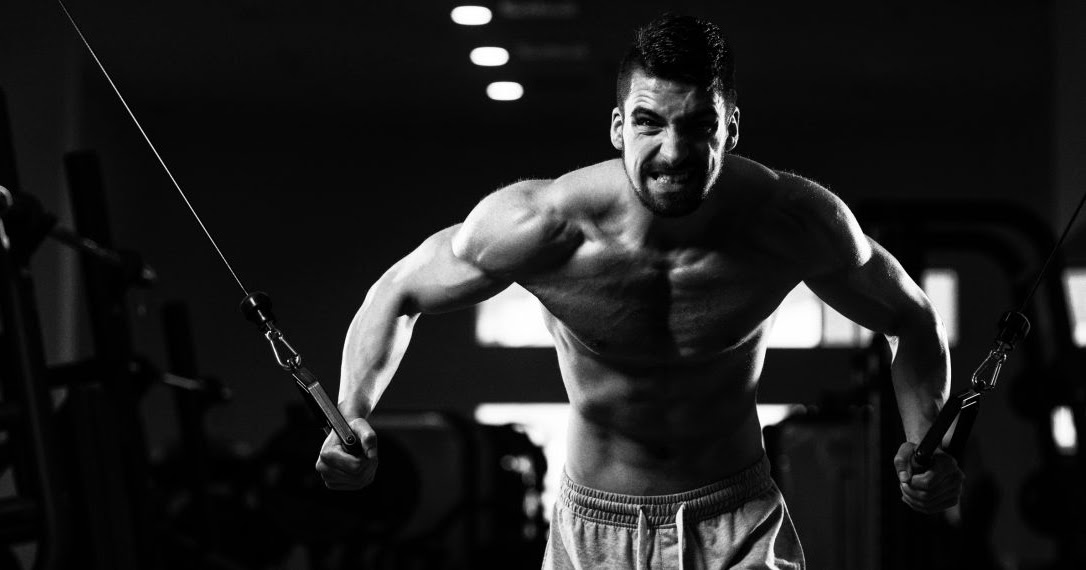 Гармоничное развитие мышц. Развитые плечи. Физические тренировки. Упражнения для развития мышц. Мужчина в зале.