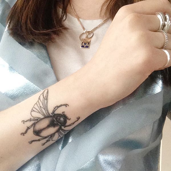 Chica con un bello tatuaje de escarabajo egipcio en su antebrazo