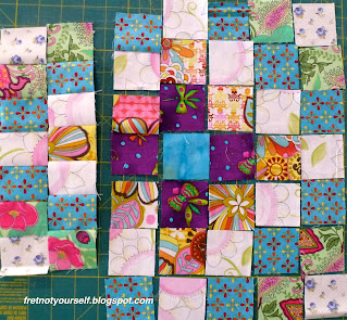 The first block, a Mini-Trip Around the World, is laid out with fabrics encircling the center square.