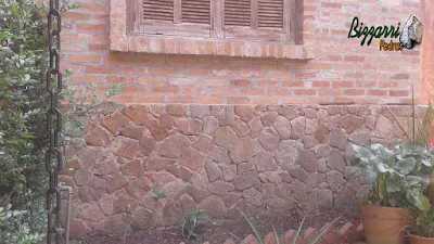 Base da casa com o revestimento de pedra moledo com a parede de tijolo a vista em condomínio em Atibaia-SP.