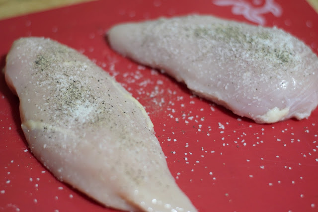 The uncooked chicken breasts seasoned with salt and pepper. 