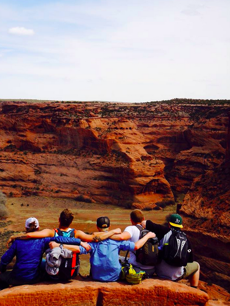 young men sitting above red canyon