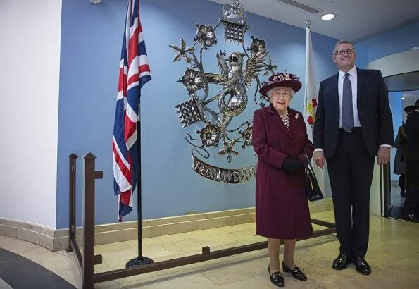 Queen Elizabeth II visited the headquarters of MI5 at Thames House in London. burgundy coat, gold brooch, floral dress