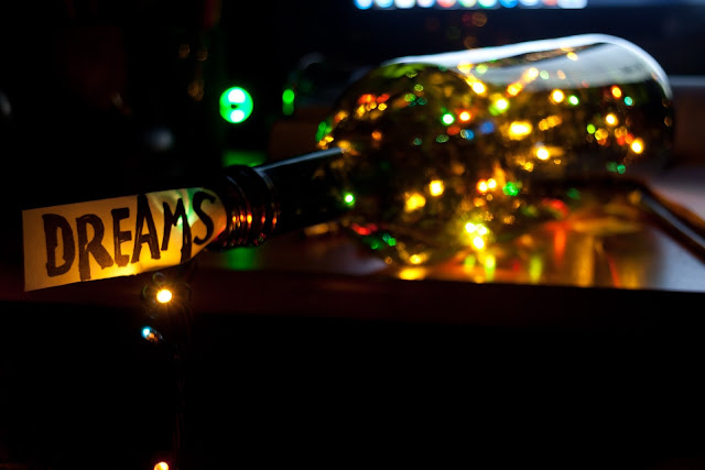 bottle with colourful lights inside, with a piece of paper sticking out with the word 'dreams' written on it