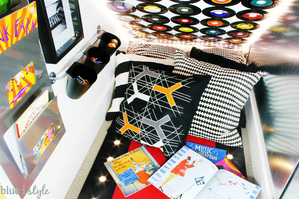 Under stairs reading nook with a collection of music books for kids in a music themed playroom.