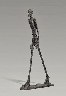 Imagen de una escultura de Giacometti, realizada en bronce en 1960, que muestra a un hombre caminando.