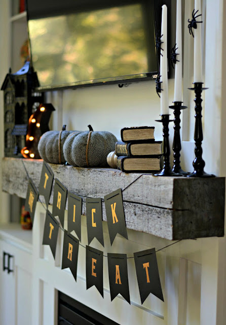 Trick or Treat banner on mantel with pumpkins and lighted hat.