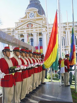 la tricolor en primer plano es izada frente al Palacio Quemado
