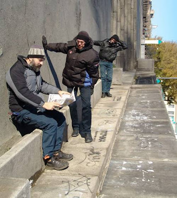 Man reading news paper and others standing