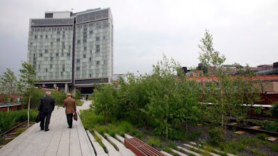 People walk on an abandoned elevated rail line that became a public park called The High Line, with the Standard Hotel in the background, in New York on Monday, June 8, 2009. (AP / Richard Drew)