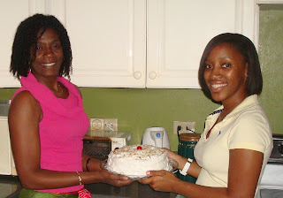 Two women holding a cake. 