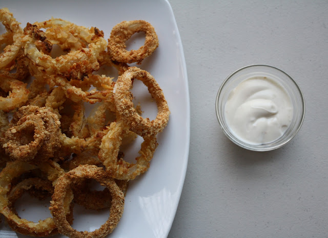 Overhead shot of oven fried onion rings on a white dish.