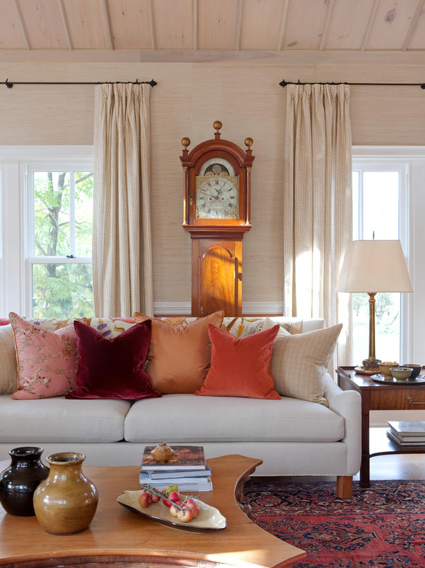 Sarah Richardson's charming living room with fall orange and red velvet pillows on white sofa as well as grandfather clock.