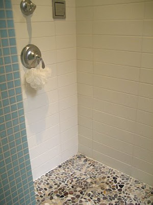 Shower in a NYC bathroom with stone floor and stacked tile walls