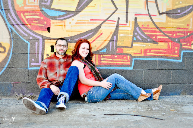 Engagement pictures taken in las vegas at the arts district with couple sitting on ground in front of a wall with grafitti