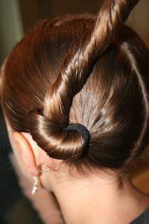 Side view of young girl's hair being styled into "Basic Twisty Buns" hairstyle