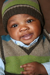 Infant baby boy smiling in a matching vest and beanie set