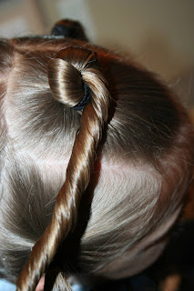 Side view of young girl's hair being styled into "Holiday Twisty Buns" hairstyle