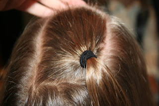 Close up view of young girl's hair being styled into "Top-Knot with Banded" Ponytail