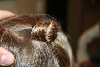 Close up view of young girl's hair being styled into "Top-Knot with Banded" Ponytail