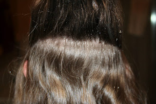 Back view of young girl's hair being styled into "Flip Braided Heart" hairstyle