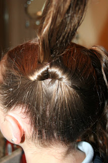 Side view of a young girl's hair being styled into “Two Hearts Twist” hairstyle