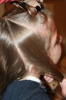 Side view of a young girl's hair being styled into “French Designer Heart” hairstyle