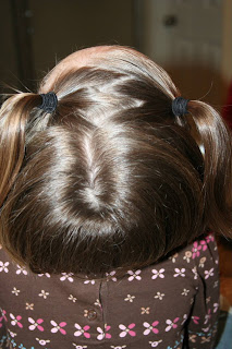 Top view of a young girl's hair being styled into “Heart Pigtail” hairstyle