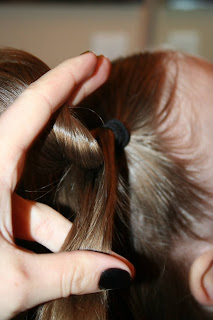 Side view of a young girl's hair being styled into “Heart Pigtail” hairstyle