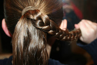 Back view of young girl's hair being styled into "bundled braids" hairstyle