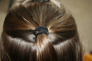 Back view of young girl's hair being styled into "The Bun-Hawk" hairstyle