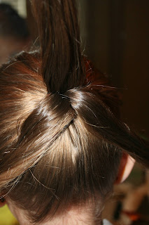 Back view of young girl's hair being styled into "Three-Leaf Clover Twists" hairstyle