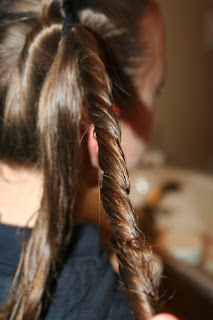 Side view of young girl's hair being styled into "Best Three-Leaf Clover" hairstyle