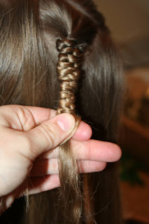 Close up view of young girl's hair being styled into "Teen Slide-Up Braid" hairstyle outside