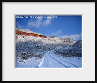 A framed photo of a narrow mountain road disappears up into the Rocky Mountains of northern Colorado on a winter day after the road has been freshly plowed.