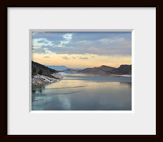 Framed photo of the approaching evening of a cold winter day paints the frozen Rocky Mountain lake in the subtle tones of a peach and pink alpine glow.